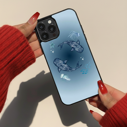 Phone case with whale design held by hands wearing red sleeves