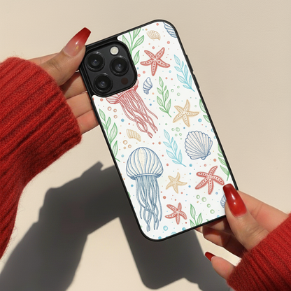 Phone case with jellyfish and starfish design held by hands wearing red sleeves.